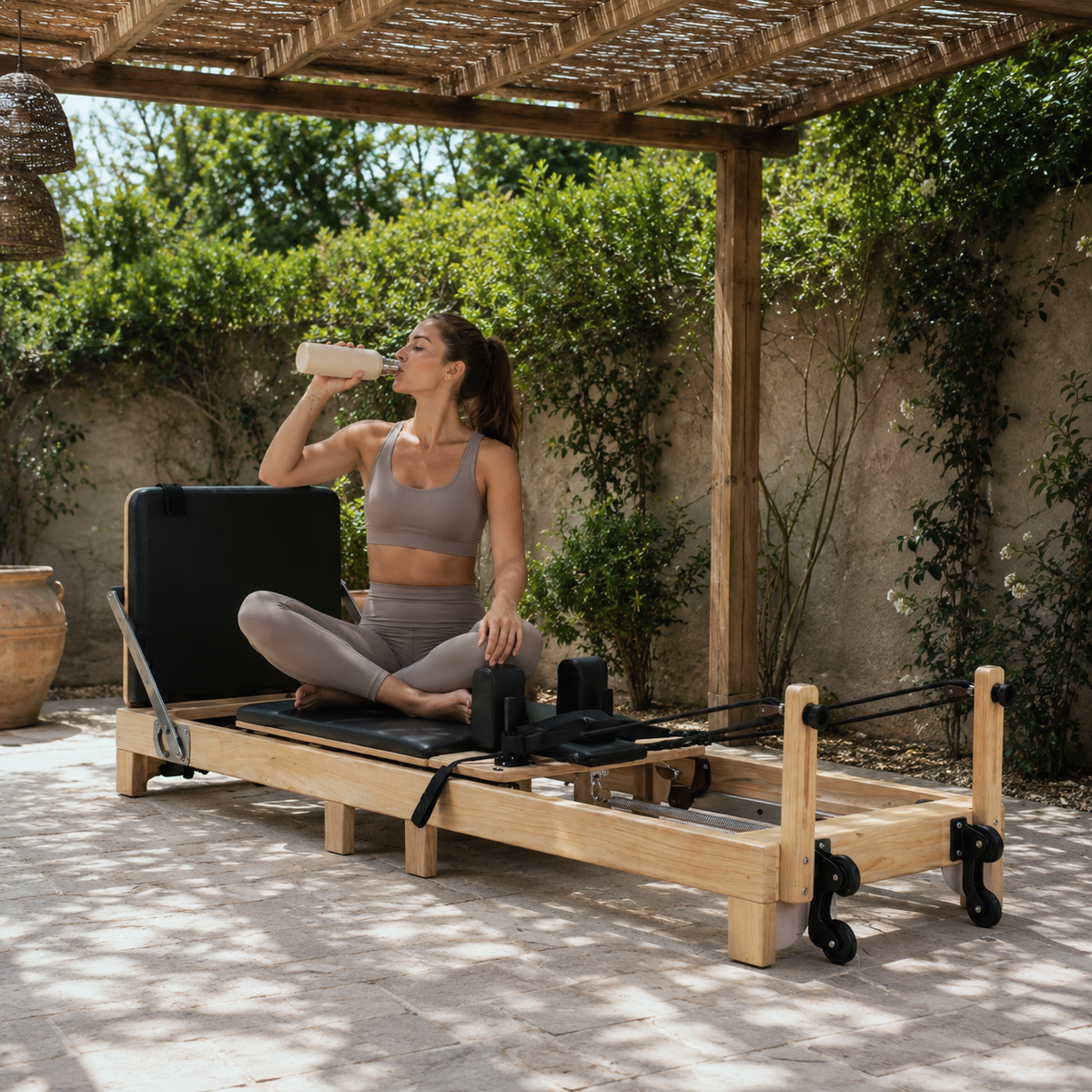 Pilates Reformer en Bois, coloris noir, avec utilisatrice